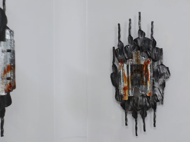 1970s Italian Brutalist lighting, this set of three wall lamps combines sculptural rigor with the refined elegance of Venetian glassmaking. Each piece features a solid, hand-crafted metal structure with bold geometric contours and a raw, expressive surface texture