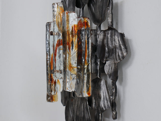 1970s Italian Brutalist lighting, this set of three wall lamps combines sculptural rigor with the refined elegance of Venetian glassmaking. Each piece features a solid, hand-crafted metal structure with bold geometric contours and a raw, expressive surface texture