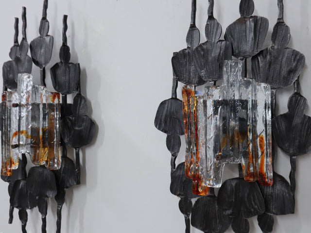 1970s Italian Brutalist lighting, this set of three wall lamps combines sculptural rigor with the refined elegance of Venetian glassmaking. Each piece features a solid, hand-crafted metal structure with bold geometric contours and a raw, expressive surface texture