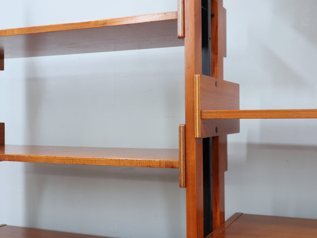 1960s teak modular bookcase a perfect balance between functionality and modernist design. The vertical wooden and metal structure supports shelves and storage modules that can be flexibly arranged