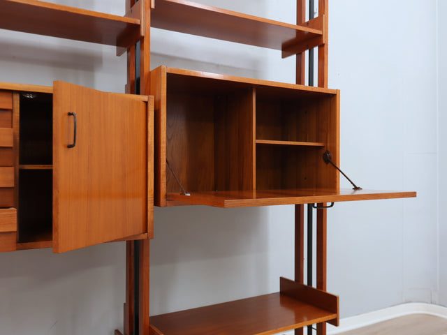 1960s teak modular bookcase a perfect balance between functionality and modernist design. The vertical wooden and metal structure supports shelves and storage modules that can be flexibly arranged