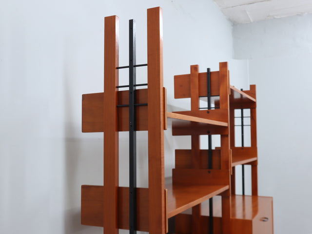 1960s teak modular bookcase a perfect balance between functionality and modernist design. The vertical wooden and metal structure supports shelves and storage modules that can be flexibly arranged