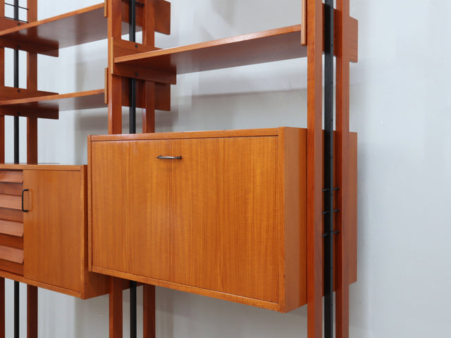1960s teak modular bookcase a perfect balance between functionality and modernist design. The vertical wooden and metal structure supports shelves and storage modules that can be flexibly arranged