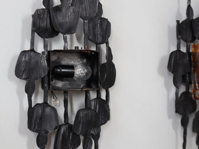 1970s Italian Brutalist lighting, this set of three wall lamps combines sculptural rigor with the refined elegance of Venetian glassmaking. Each piece features a solid, hand-crafted metal structure with bold geometric contours and a raw, expressive surface texture