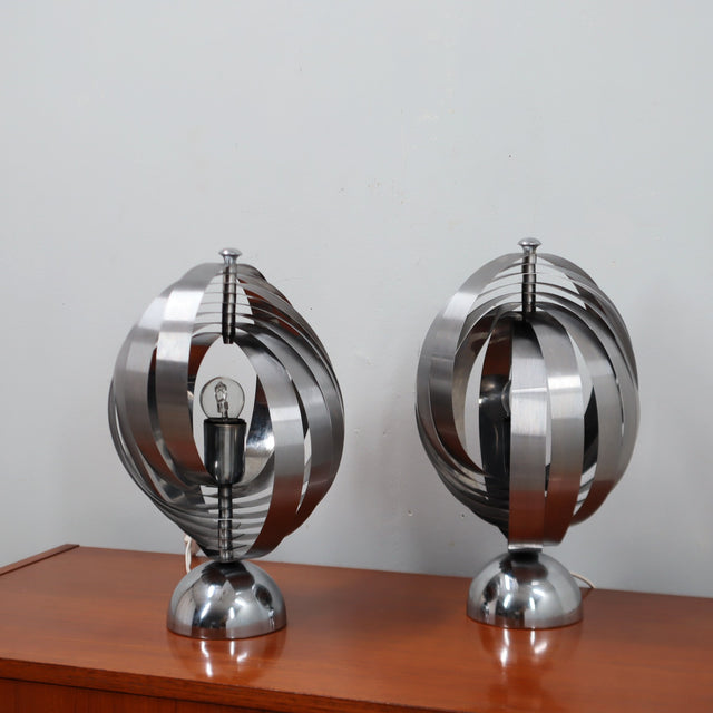 Pair of 1970s Henri Mathieu French kinetic spiral table lamps in brushed steel and chrome illuminated on a wooden sideboard