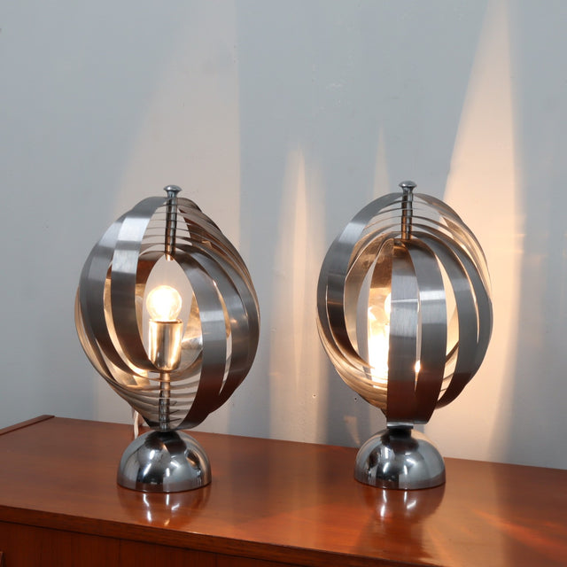 Pair of 1970s Henri Mathieu French kinetic spiral table lamps in brushed steel and chrome illuminated on a wooden sideboard