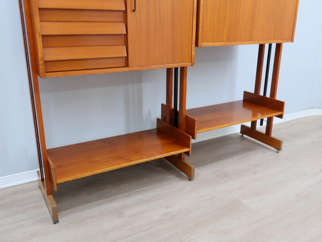 1960s teak modular bookcase a perfect balance between functionality and modernist design. The vertical wooden and metal structure supports shelves and storage modules that can be flexibly arranged