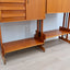 1960s teak modular bookcase a perfect balance between functionality and modernist design. The vertical wooden and metal structure supports shelves and storage modules that can be flexibly arranged