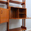 1960s teak modular bookcase a perfect balance between functionality and modernist design. The vertical wooden and metal structure supports shelves and storage modules that can be flexibly arranged