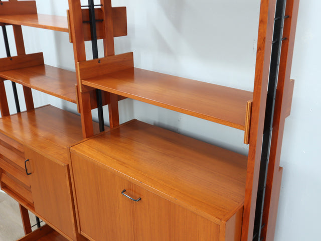 1960s teak modular bookcase a perfect balance between functionality and modernist design. The vertical wooden and metal structure supports shelves and storage modules that can be flexibly arranged